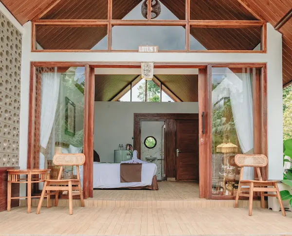 Open glass doors of a cottage terrace, with two rattan chairs and side tables