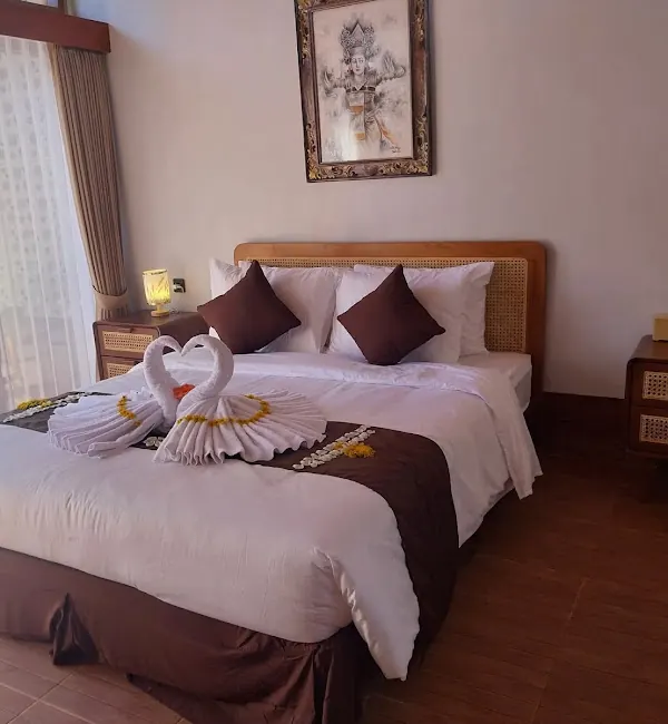 Double room with a rattan headboard, towel swans and a Balinese dancer painting
