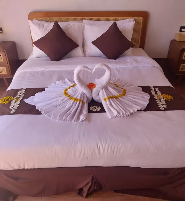 Double bed decorated with towel swans and frangipani flowers