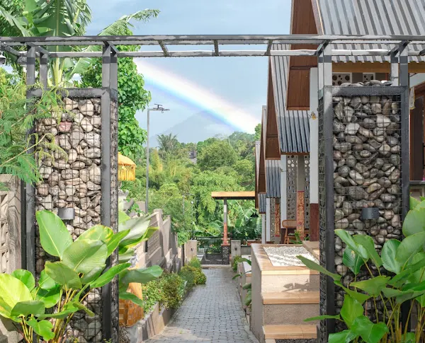 A rainbow over the treetops, seen from the villa's garden path between stone gabion pillars